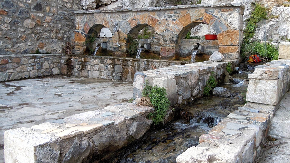 Traditional stone spring with flowing mountain water in Meronas village, Crete
