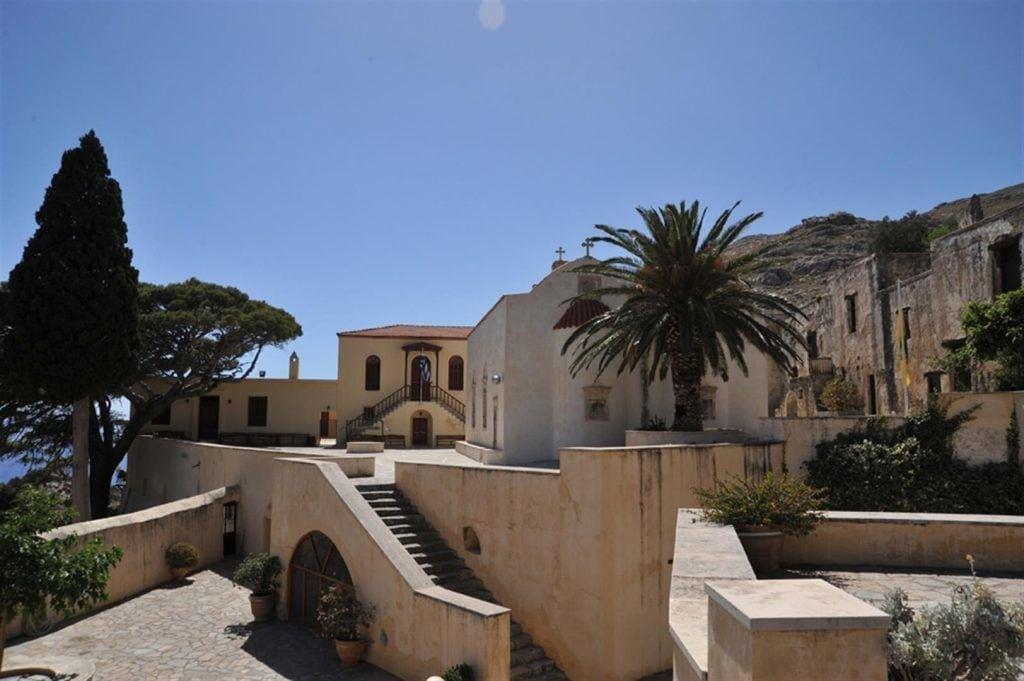 The historic Preveli Monastery in South Crete, with stone buildings, palm tree and steps leading to the courtyard